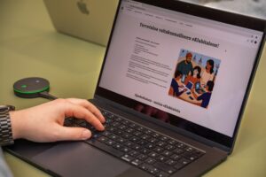 Käsi kannettavan tietokoneen näppäimistöllä. Näytöllä on valtakunnallisen eKlubitalon etusivu.