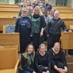 Hymyileviä ihmisiä seisomassa luentosalin portaikossa.