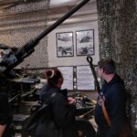 Kaksi henkilöä museossa katsomassa seinällä olevia kuvia.